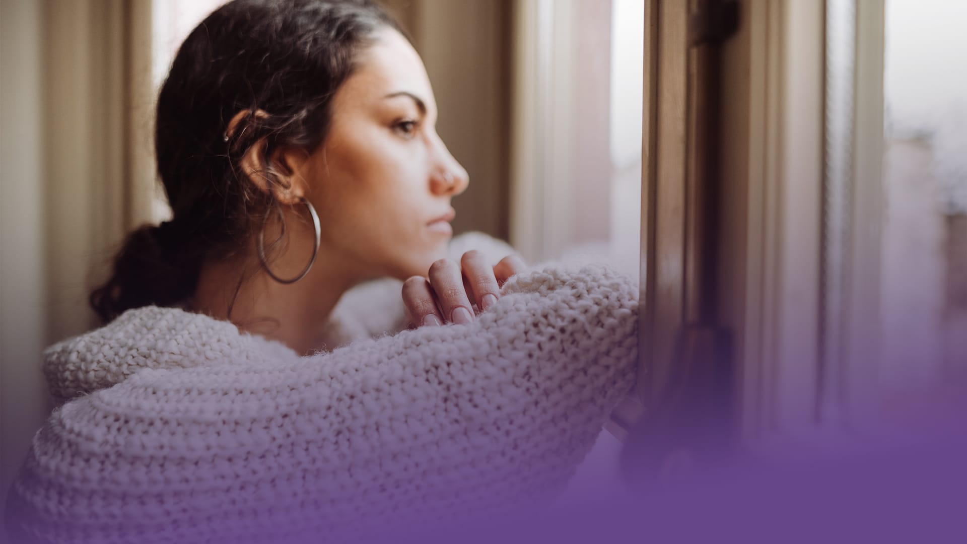 Ung kvinna tittar ut genom fönster, med lila bård för att uppmärksamma Purple Day